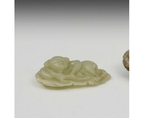 A Chinese pale celadon jade carved pendant, depicting a recumbent figure upon a lotus leaf, 5.4cm. long.