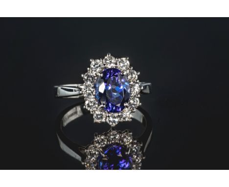 An 18ct white gold, Tanzanite and diamond cluster ring, the oval cut 2.43ct Tanzanite within a border of twelve brilliant cut