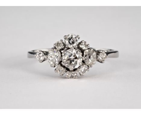 A vintage 18ct white gold and diamond cluster ring, 1930s-40s, the central brilliant cut diamond within a shaped border of br