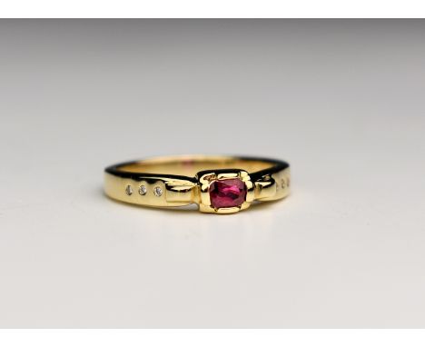 An 18ct yellow gold, ruby and diamond ring, the oval cut ruby over in an oblong four claw setting over shoulders inset with s