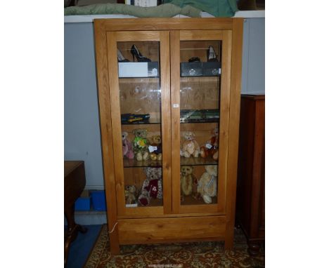 A contemporary light Oak display cabinet having a pair of opposing glazed doors, a full-width drawer below and having an illu