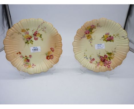 A pair of Royal Worcester blush ivory plates, painted flowers and foliage with ribbing and undulating gilt rim, code for 1904