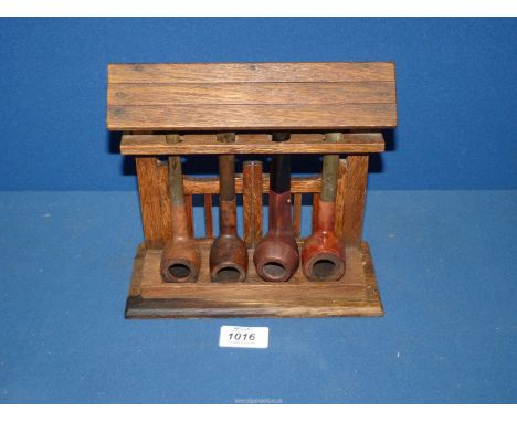 An oak four bay Pipe Rack, fashioned as a roofed lych gate holding three briar pipes, etc.
