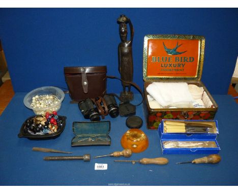 A box of miscellanea including costume jewellery, boxed set of dessert knives & forks, African carving, old Bluebird tin cont