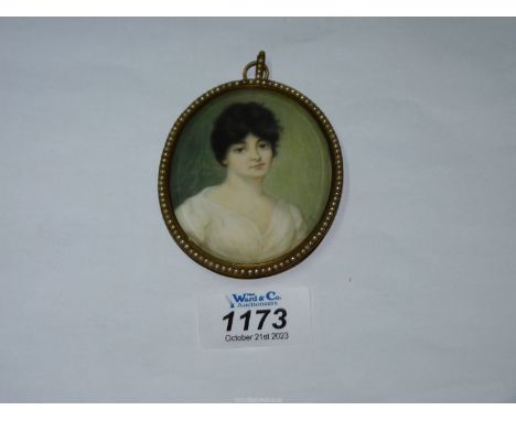 An oval framed miniature of a dark haired lady in peasant style blouse, no visible signature but a capital 'E' to the right o