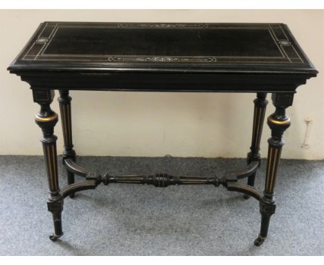 A Victorian aesthetic movement card table with black ebonised rectangular turn over top, red baize lined interior, four turne