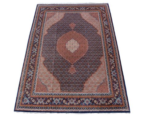 A Tabriz carpet, the dark field with central madder medallion its self incorporating a cream medallion, within light blue spa
