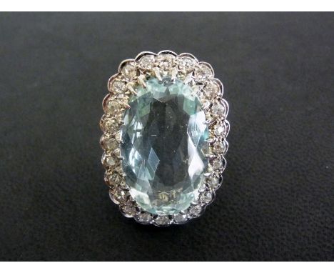 An 18ct gold aquamarine and diamond cluster ring - The oval aquamarine within an old-cut diamond surround to the plain band -