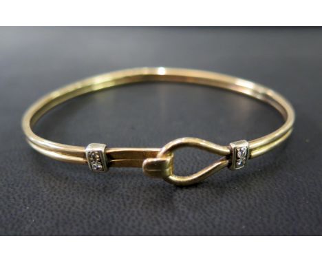 A 9ct gold diamond bangle -The grooved bangle to the brilliant-cut diamond panels and hook over clasp - Estimated total diamo