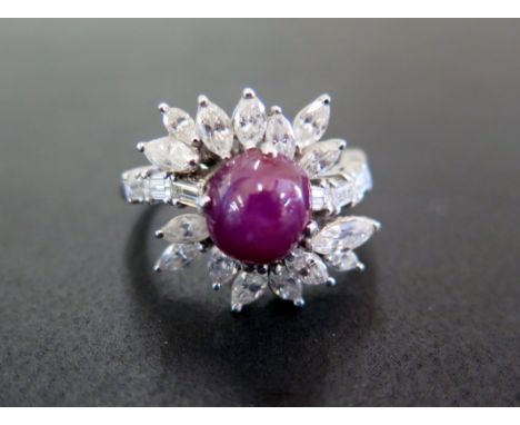 A star ruby and diamond cluster ring - Of crossover design, the circular ruby cabochon within a marquise-shape diamond surrou