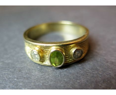 A Peridot and diamond three stone gold ring - diamonds approx 3mm diameter - Peridot approx 4mm x 3mm - gold tests as 14ct - 