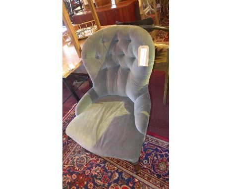 A Victorian spoon back armchair, with blue velour button back upholstery, raised on turned legs and castors 