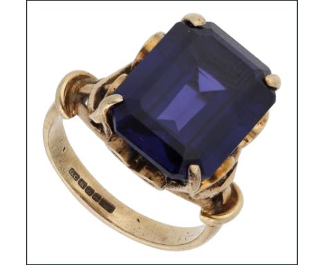A 9ct synthetic sapphire ring, the step-cut synthetic sapphire claw set to a 9ct gold scrollwork mount, ring size G. £100-£15