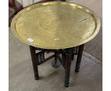 An Eastern brass topped folding occasional table and a pierced brass fender 