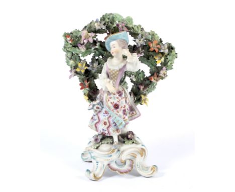 A 19th century Continental porcelain Chelsea figure. Depicting a lady framed by a panel of garlands of flowers and leave rais