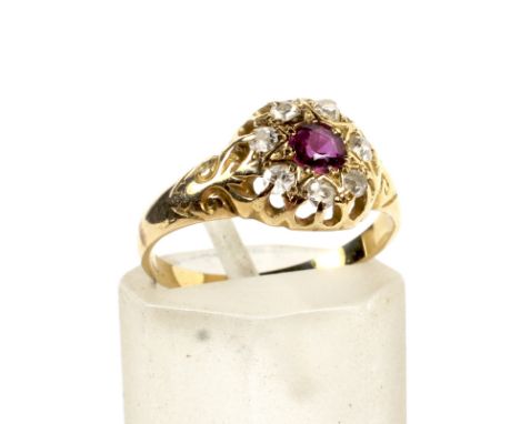 A WWI yellow metal ruby and diamond dress ring. The central ruby surrounded by seven old cut diamonds set in a vintage circul