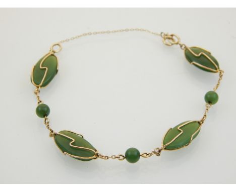A jade bracelet, set in 9ct gold wire and fine chain links.