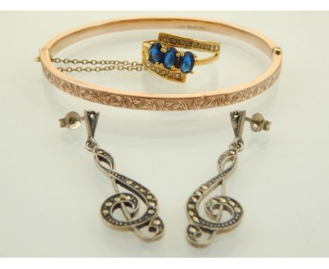 A 9ct rose gold engraved hinged bangle, a pair of silver and marcasite clef shaped earrings and a yellow metal blue stone dre