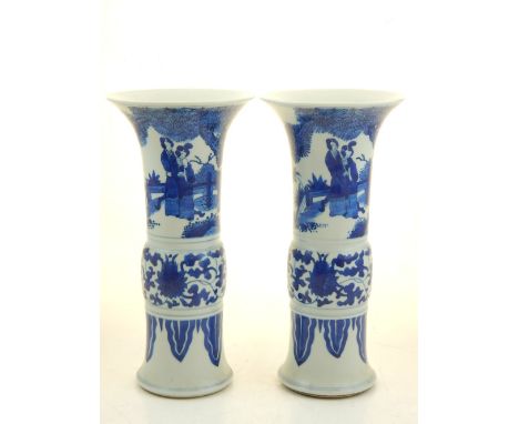 A pair of Chinese blue and white gu shaped vases, decorated with figures in a garden setting, both bear double blue circle to