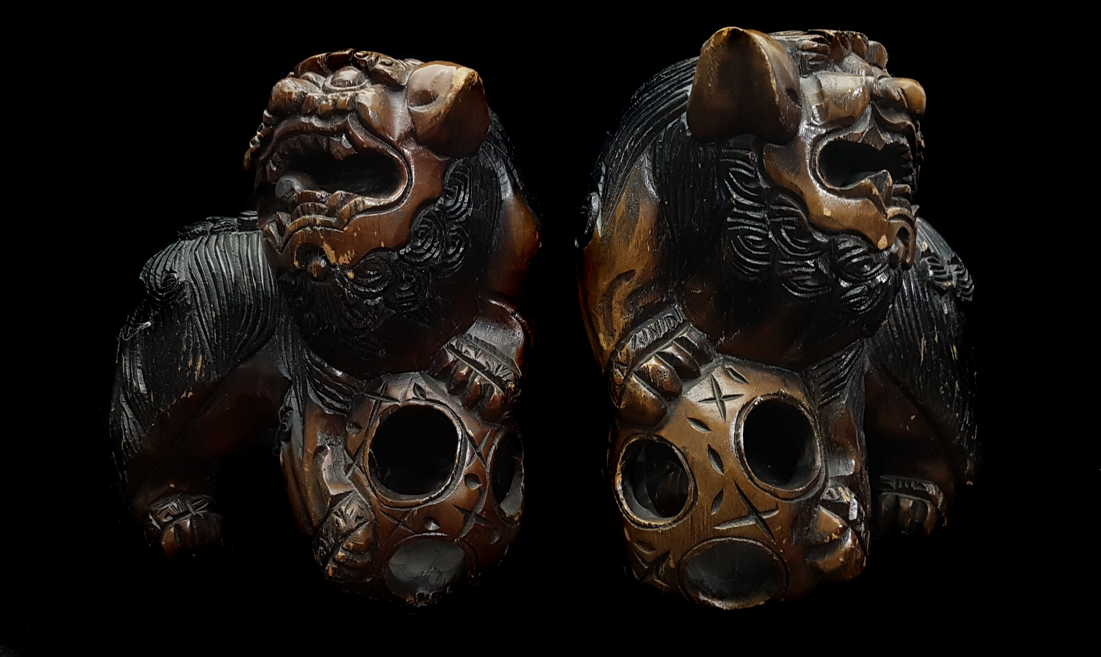 A pair of Chinese carved wood Dogs of Fo, each with paw resting on a