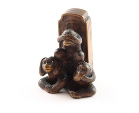 NETSUKE SANBIKI SARU, Holz, Augen schwarzes Horn, sign., die drei Affen (sanbiki saru) vor einer Stele mit dem Schriftzeichen
