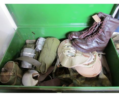 A metal trunk of military clothing including boots, mess tins and head wear