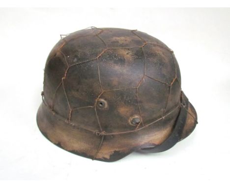 A copy of a German M40 helmet with distressed tan paintwork and mesh covering