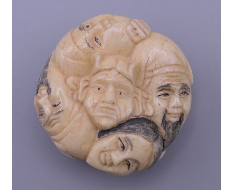 A bone netsuke formed as faces.  4 cm diameter.