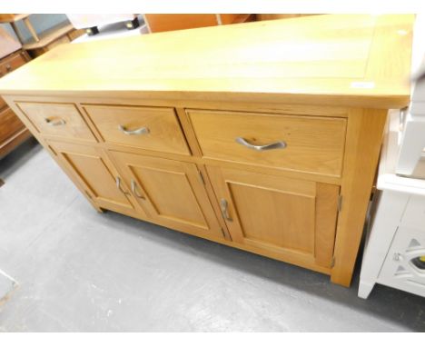 A light oak sideboard with three drawers above a triple cupboard