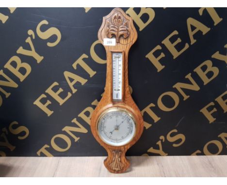 AN ANEROID BAROMETER IN CARVED OAK CASE