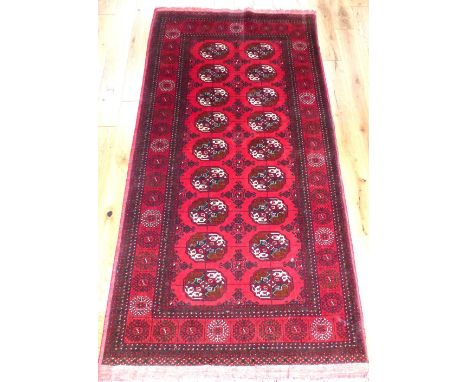 Turkoman style carpet, traditionally decorated with elephant pad medallions to centre within reticulated border, 220x170cm