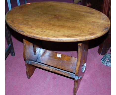 An oak oval low occasional table having book trough undertier