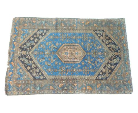A large rug with blue ground, beige central hexagonal lozenge encased in a dark blue bracket design, 127 by 95cm. 