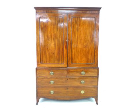 A Regency mahogany press cupboard, two panelled doors enclosing a hanging rail, over two short and two long drawers with cock