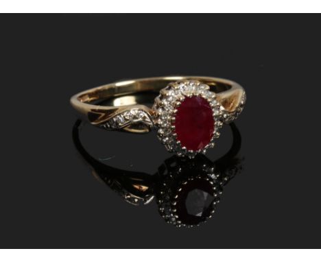 A 9ct gold halo cluster ring set with a ruby under a border of diamonds, size T.