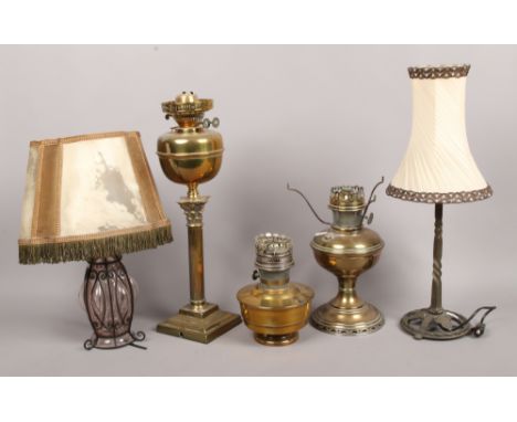 Three brass based oil lamps to include Corinthian column, along with a wrought iron and wire work table lamp.