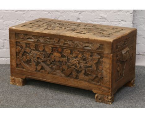 A camphor wood chest carved with dragons and raised on bracket supports.