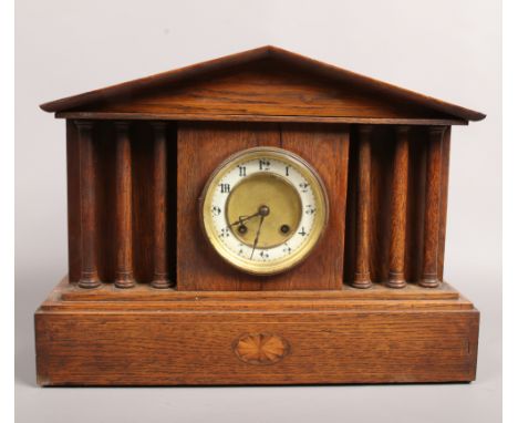 An 8 day oak mantle clock with column supports, chiming on a coiled gong with key.