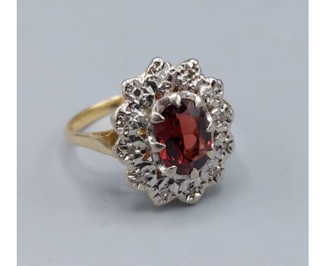 An 18ct gold cluster ring set with a central oval Garnet surrounded by Diamonds, 3.8gms, ring size M 