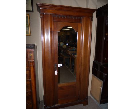 A 19th Century walnut wardrobe with flared cornice over a single arched mirror panelled door enclosing hanging space and a sh