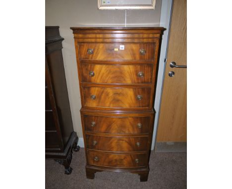 A reproduction mahogany bowfront miniature chest on chest, six drawers with ring-pull handles, raised on bracket feet.