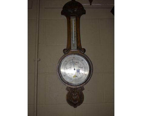 An aneroid barometer and thermometer in carved and stained oak banjo patterned case (missing glass cover from the barometer).