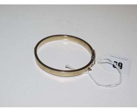 A 9ct. gold hollow cast bangle half engraved with foliate decoration, 8grms.