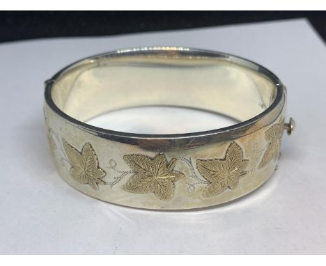 A HALLMARKED BIRMINGHAM SILVER BANGLE WITH GILDED IVY DESIGN IN A PRESENTATION BOX GROSS WEIGHT 58.8 GRAMS 