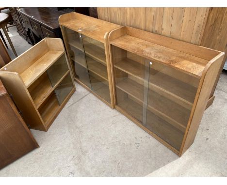 THREE LIGHT OAK BOOKCASES WITH GLASS SLIDING DOORS, TWO BEING 35" WIDE AND ONE 30", ONE BEARING LABEL 'THE PHOENIX GALLERY' 