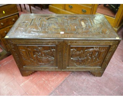 An Oriental carved camphorwood two door chest on step bracket feet, twin opening front doors revealing interior shelves and d