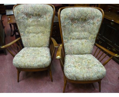 A pair of Ercol stick back armchairs with button upholstered backs and seats