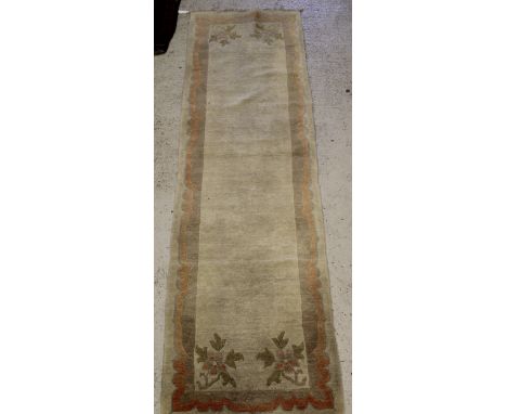 A Tibetan runner, the central panel of plain colouring and simple floral decoration to the corners within a stepped cream, bl