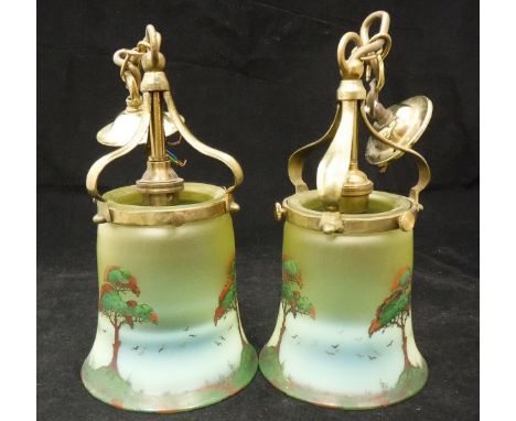 A pair of Arts & Crafts style hanging lamps, the brass mounts supporting coloured glass shades, each with painted scenes of t
