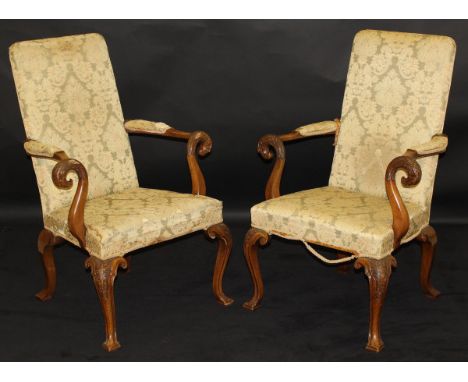 A pair of 19th Century mahogany arm chairs in a green and yellow flock upholstery, with show arm frames, the arm rests carved